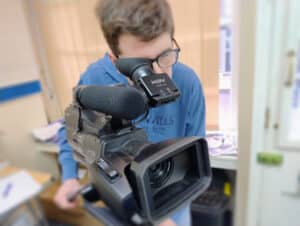 A man looks through the viewfinder of a video camera